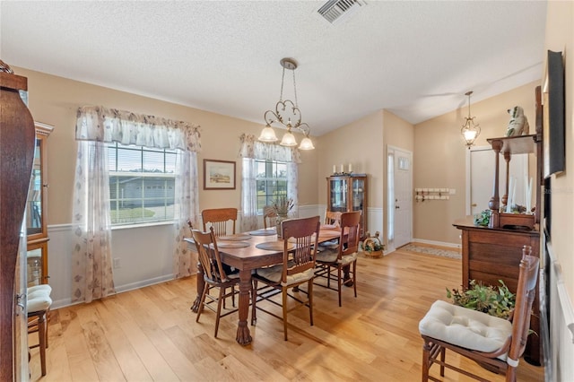 dining space with light hardwood / wood-style floors and a textured ceiling