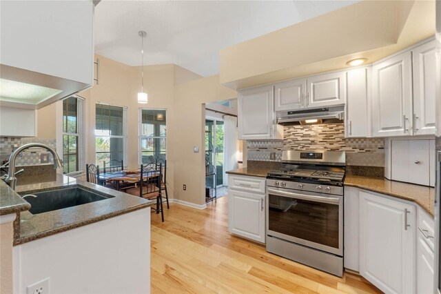 kitchen with white cabinetry, stainless steel gas range, dark stone countertops, pendant lighting, and sink