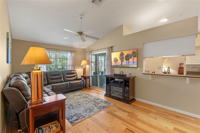 living room with light hardwood / wood-style floors, a textured ceiling, lofted ceiling, and ceiling fan