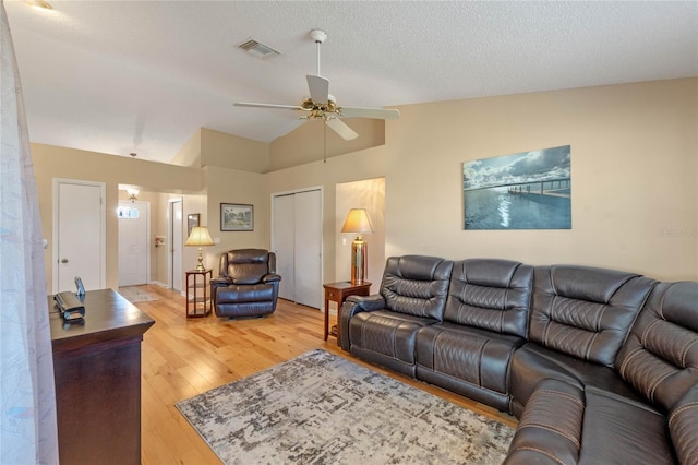 living room featuring hardwood / wood-style flooring, a textured ceiling, lofted ceiling, and ceiling fan