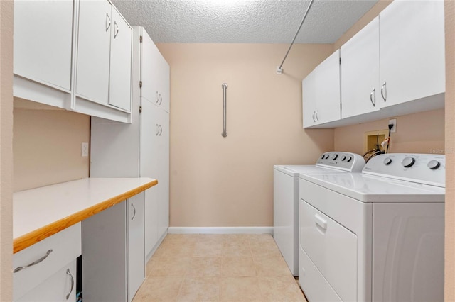 washroom featuring a textured ceiling, cabinets, and washer and clothes dryer