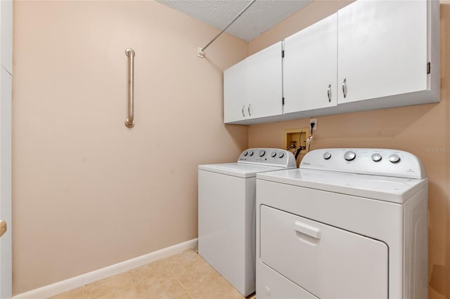 washroom featuring cabinets, a textured ceiling, and washer and clothes dryer