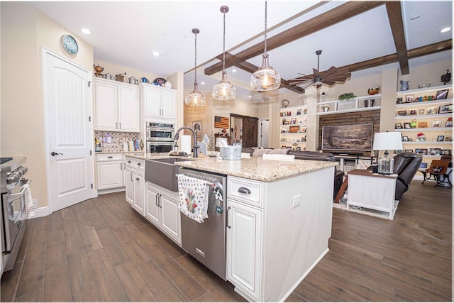 kitchen with a center island with sink, beam ceiling, white cabinetry, and hanging light fixtures