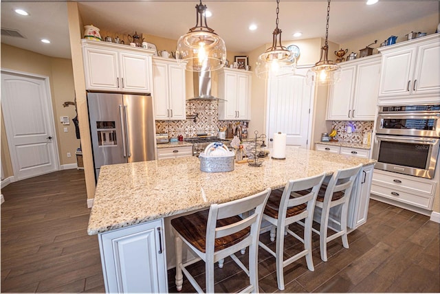 kitchen with white cabinets, stainless steel appliances, decorative light fixtures, and a spacious island