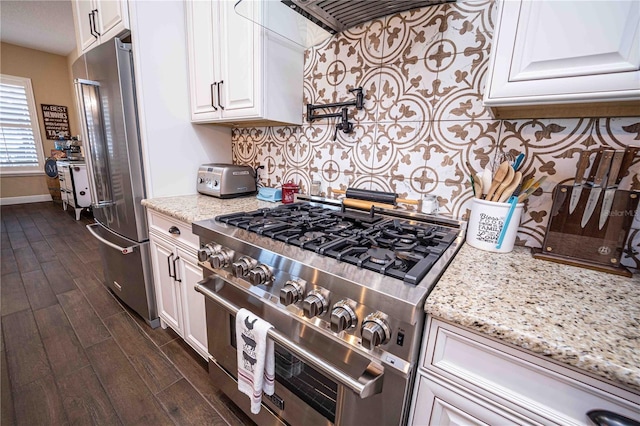 kitchen featuring high end appliances, light stone countertops, dark wood-type flooring, decorative backsplash, and white cabinets