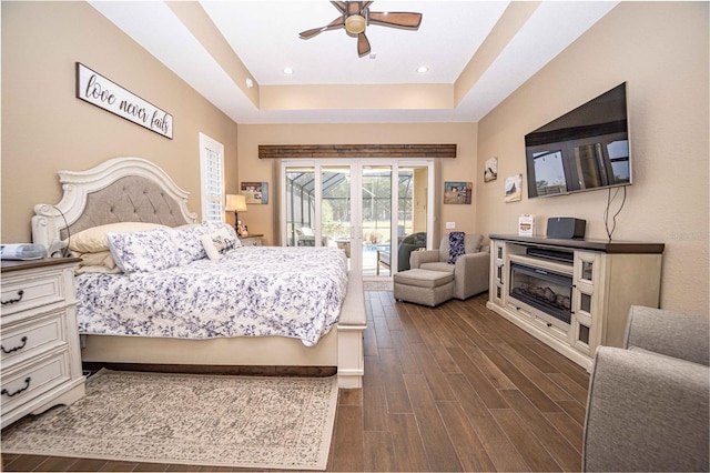 bedroom featuring a raised ceiling, ceiling fan, access to exterior, and dark hardwood / wood-style floors