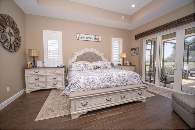 bedroom with access to outside, a tray ceiling, and multiple windows