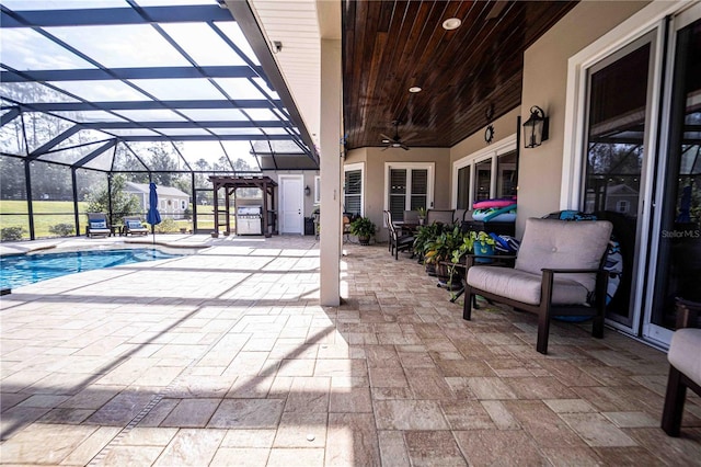 view of swimming pool featuring a patio area, ceiling fan, and glass enclosure