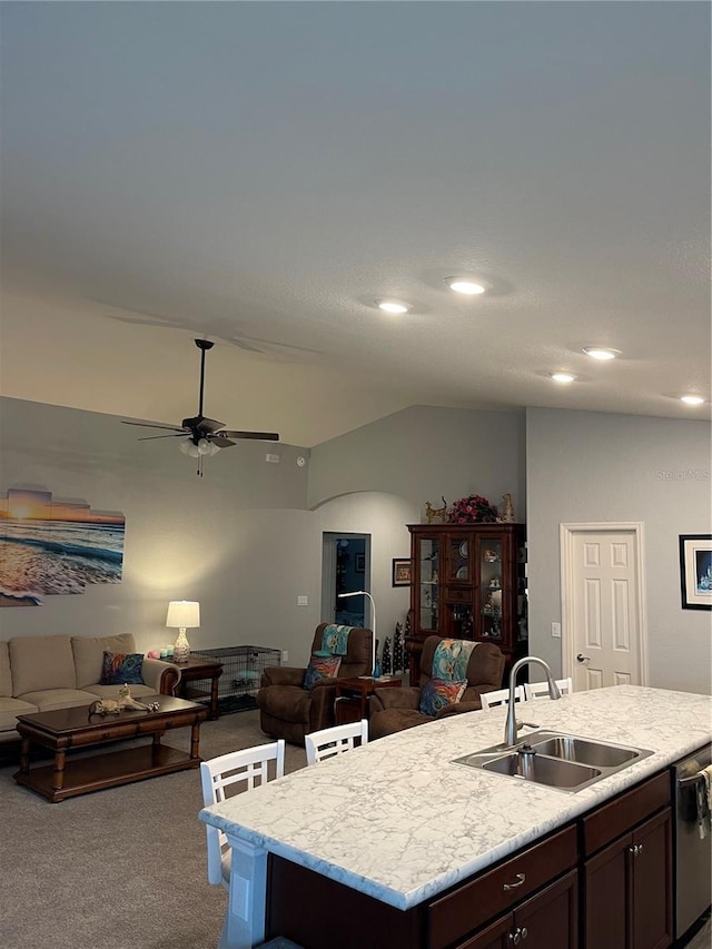 kitchen featuring carpet, sink, ceiling fan, stainless steel dishwasher, and a center island with sink