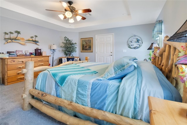 carpeted bedroom featuring ceiling fan and a tray ceiling