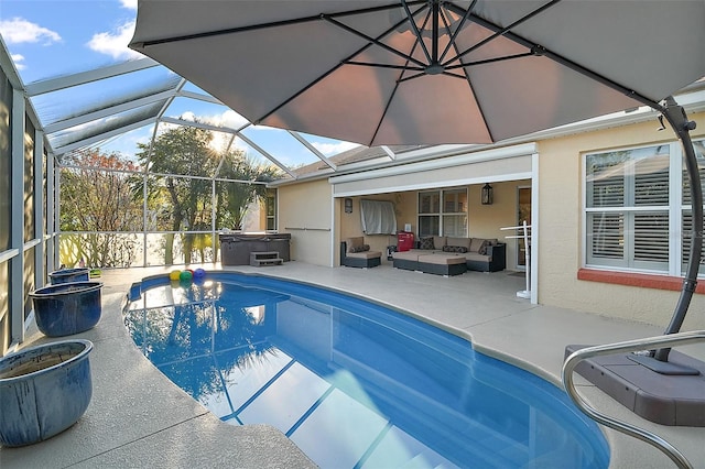 view of pool with a hot tub, glass enclosure, outdoor lounge area, and a patio