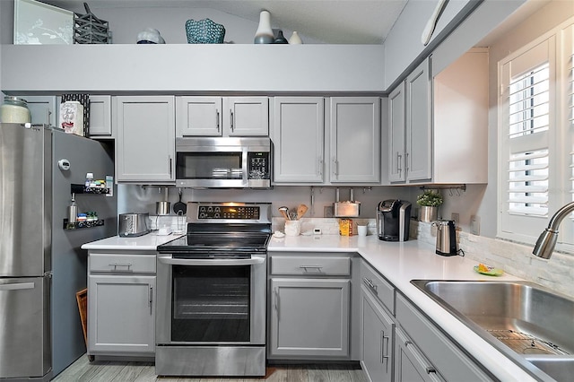 kitchen with appliances with stainless steel finishes, gray cabinetry, and sink