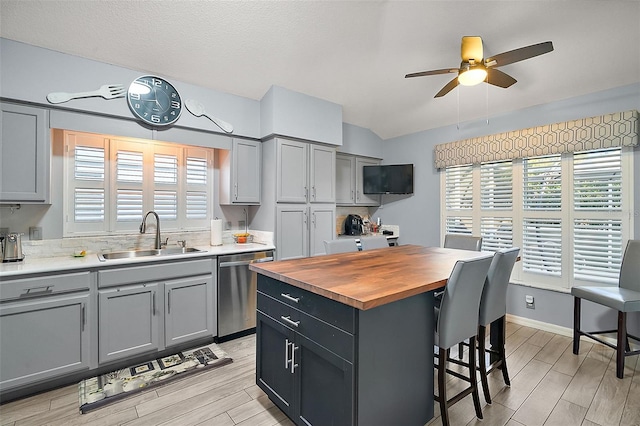 kitchen with stainless steel dishwasher, a kitchen island, gray cabinets, ceiling fan, and sink