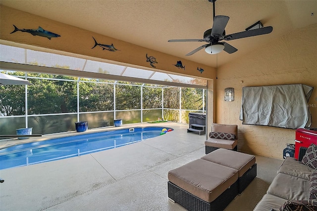 view of swimming pool with ceiling fan, a lanai, and a patio area