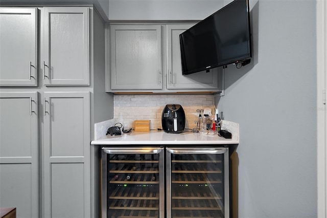 bar with beverage cooler, gray cabinets, and tasteful backsplash