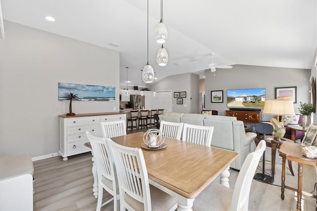 dining area with ceiling fan, vaulted ceiling, and light wood-type flooring