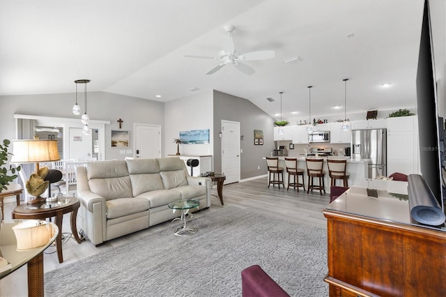 living room featuring ceiling fan, light wood-type flooring, and vaulted ceiling