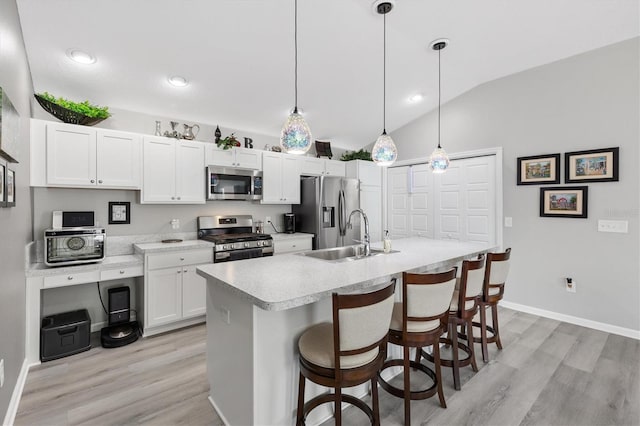 kitchen featuring pendant lighting, white cabinets, lofted ceiling, stainless steel appliances, and sink