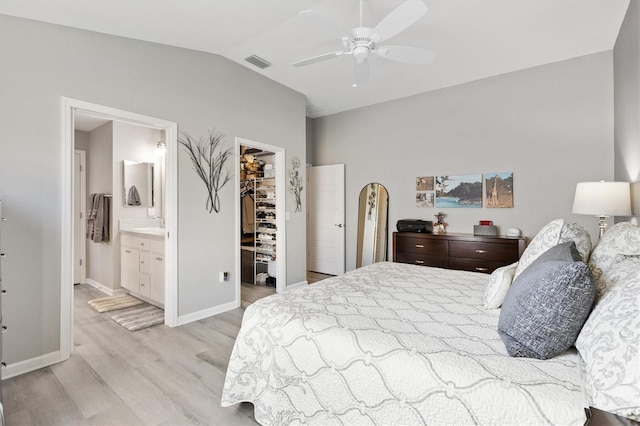 bedroom featuring ceiling fan, vaulted ceiling, ensuite bath, a walk in closet, and a closet