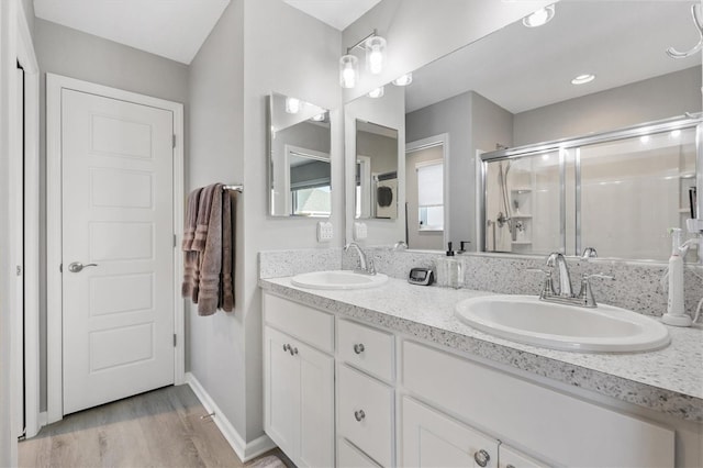 bathroom featuring vanity, washer / clothes dryer, a shower with door, and hardwood / wood-style flooring