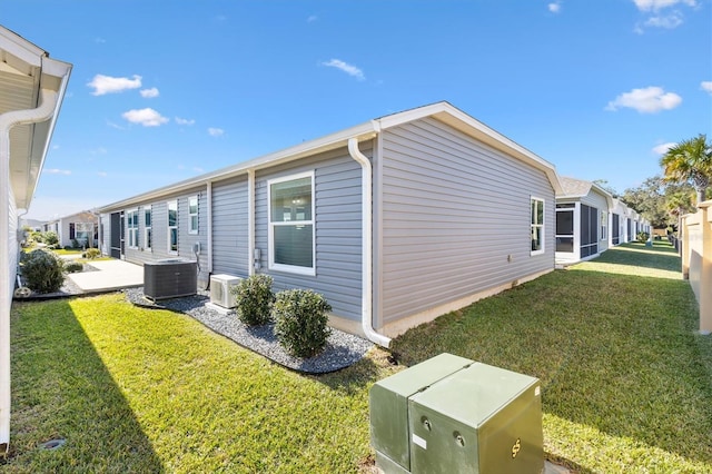 view of property exterior with central AC and a yard