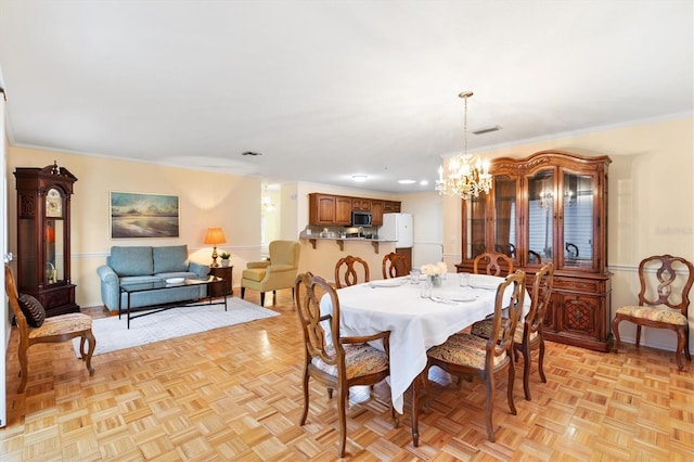 dining room with a chandelier, light parquet floors, and crown molding