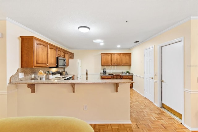 kitchen featuring electric range, kitchen peninsula, white fridge, a breakfast bar area, and light parquet flooring