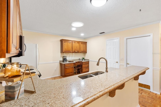 kitchen featuring light stone countertops, a kitchen bar, ornamental molding, and sink