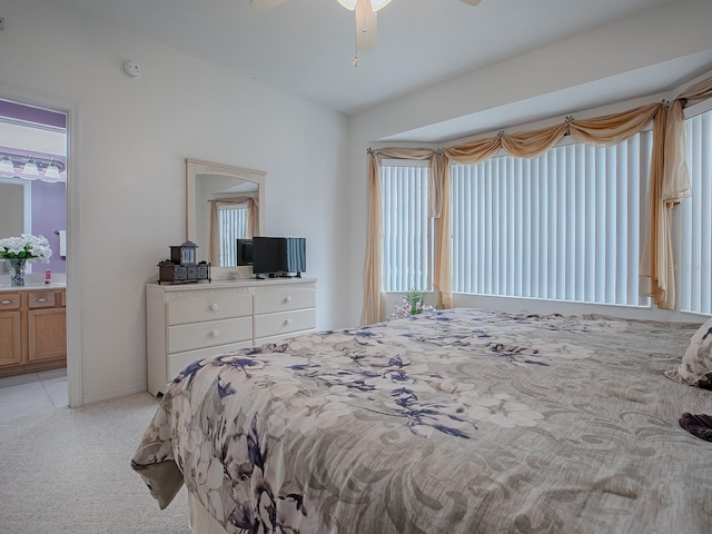 bedroom featuring light colored carpet, ceiling fan, and connected bathroom