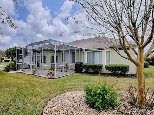 back of property featuring a patio, glass enclosure, and a lawn