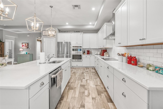 kitchen with white cabinetry, a large island, appliances with stainless steel finishes, decorative light fixtures, and sink