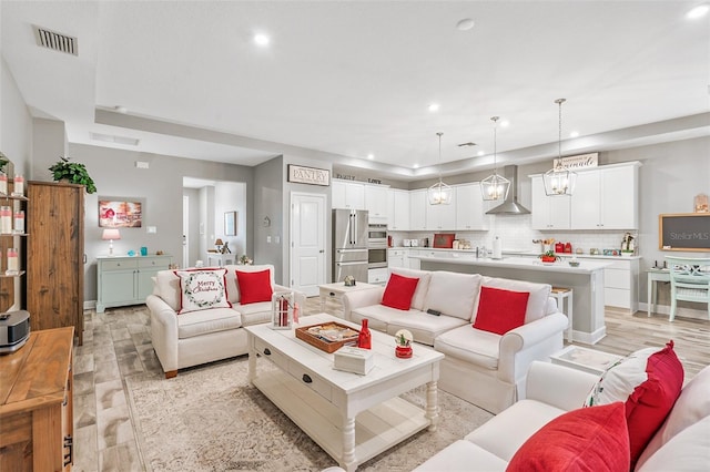 living room featuring a raised ceiling, light wood-type flooring, and a chandelier