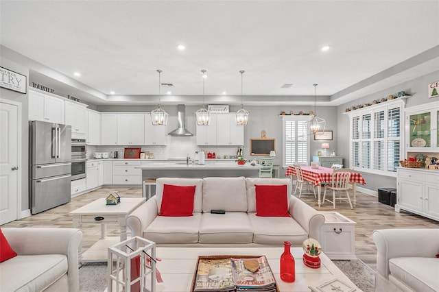 living room with sink, a tray ceiling, and light hardwood / wood-style flooring