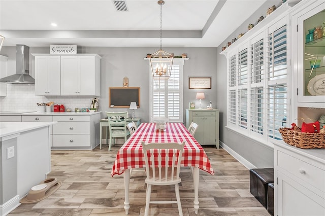 dining room featuring light wood-type flooring, a notable chandelier, and a tray ceiling