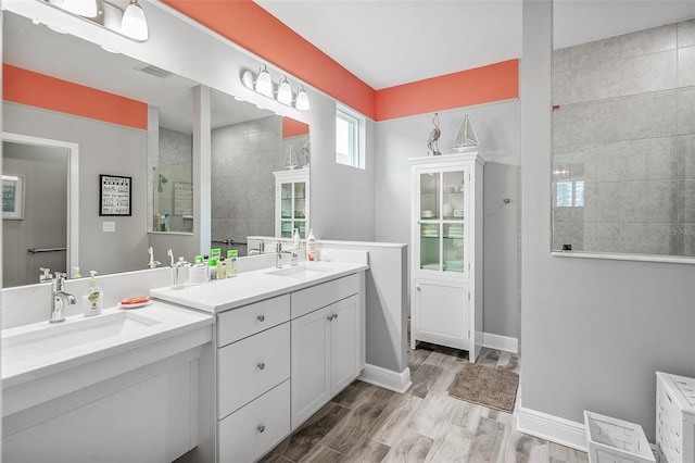 bathroom with a tile shower, wood-type flooring, and vanity