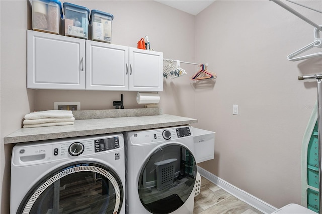 laundry room featuring cabinets, light hardwood / wood-style floors, and washing machine and clothes dryer