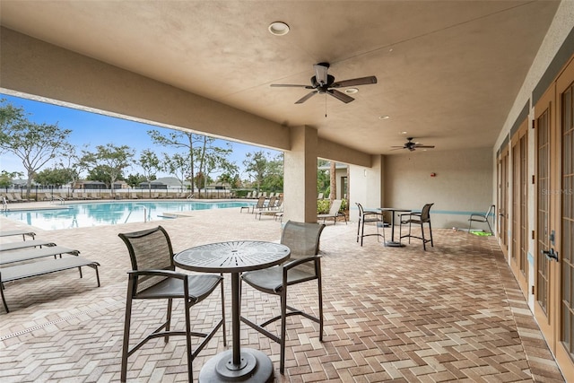 view of patio with ceiling fan and a community pool