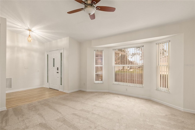 empty room with carpet, visible vents, ceiling fan, and baseboards