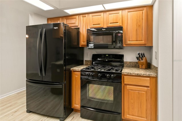 kitchen with black appliances, light wood-style flooring, and baseboards