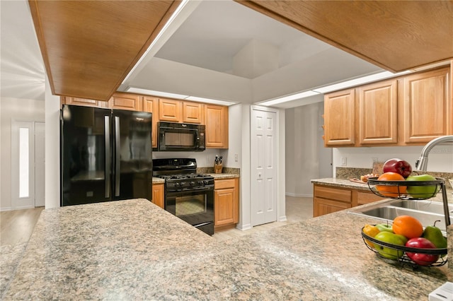 kitchen with black appliances, a sink, light countertops, and baseboards