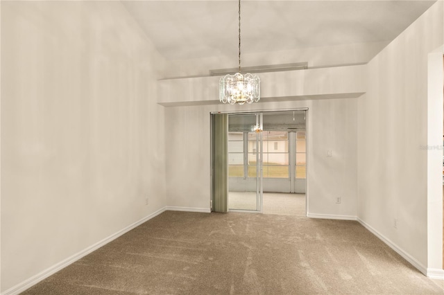 carpeted spare room with baseboards and an inviting chandelier