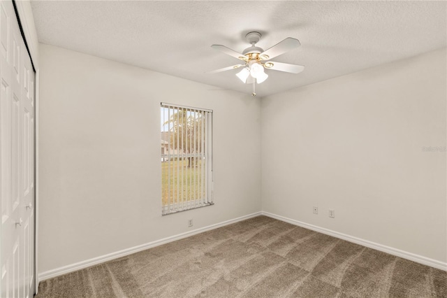 carpeted spare room featuring a ceiling fan, a textured ceiling, and baseboards