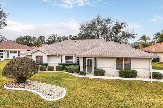 ranch-style house with a shingled roof, a front yard, and stucco siding