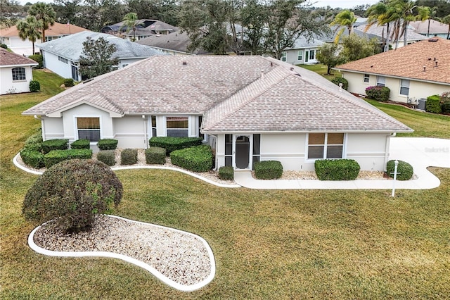 view of front facade with central air condition unit, roof with shingles, a residential view, stucco siding, and a front yard