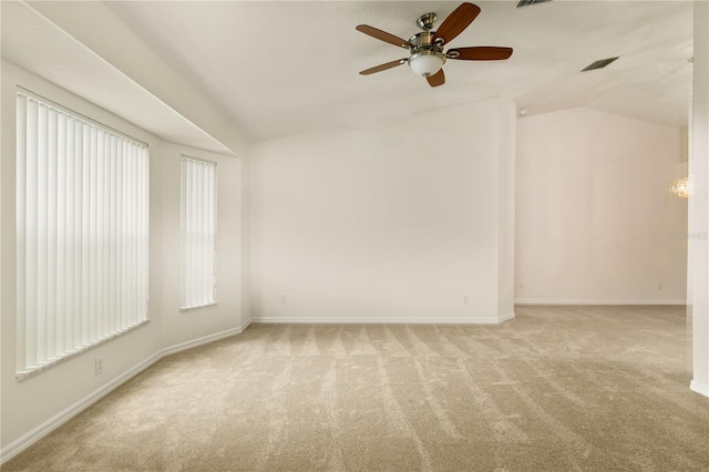 carpeted empty room with visible vents, vaulted ceiling, baseboards, and ceiling fan