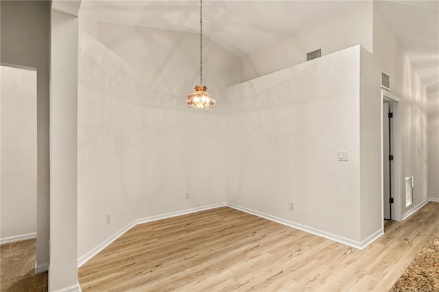 unfurnished dining area featuring light wood-type flooring, baseboards, visible vents, and vaulted ceiling