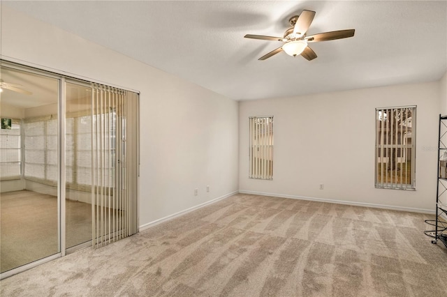 carpeted empty room featuring a ceiling fan and baseboards