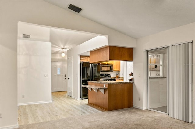 kitchen with a peninsula, black appliances, visible vents, and lofted ceiling