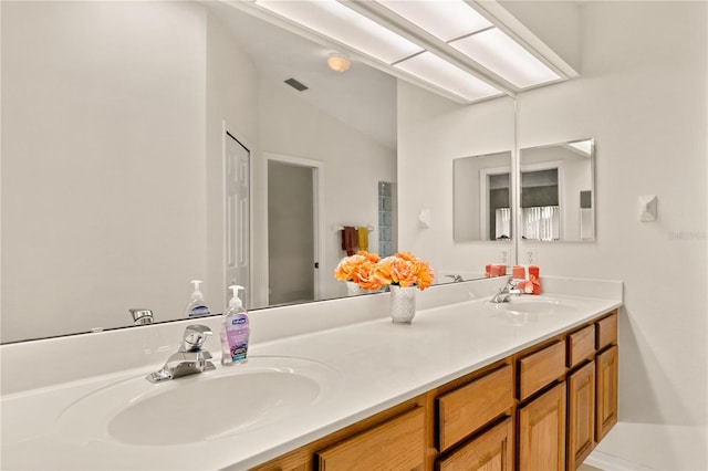 bathroom with lofted ceiling, visible vents, a sink, and double vanity