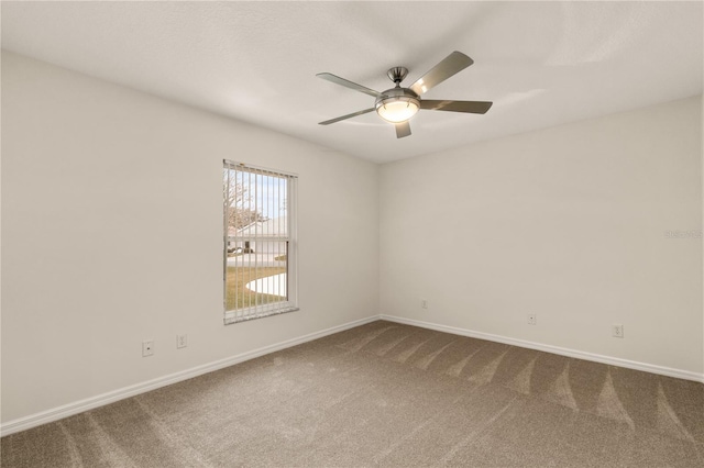 empty room with a ceiling fan, dark carpet, and baseboards